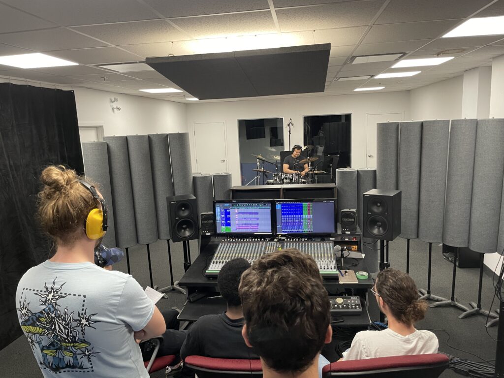 Audio engineering students observing a drummer from the mixing room – Musitechnic Montreal school